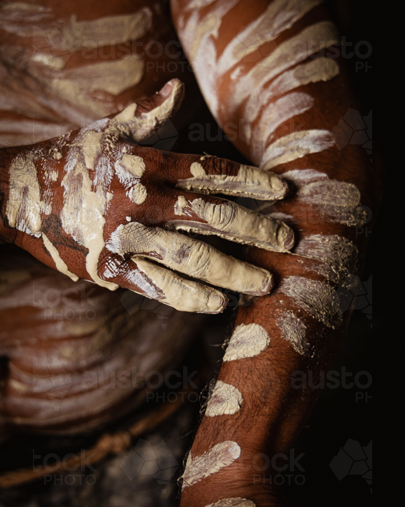 Aboriginal man painting up arm with ochre - Australian Stock Image
