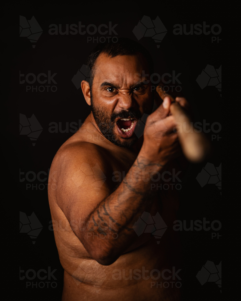 Aboriginal man pointing spear forward yelling - Australian Stock Image