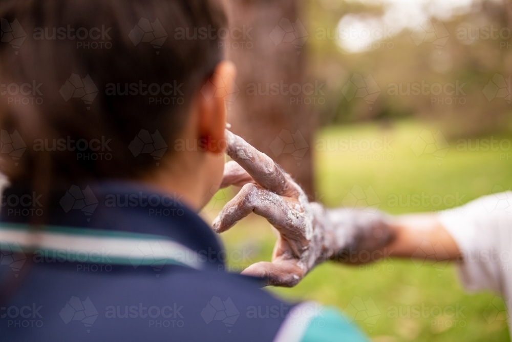 Aboriginal man putting white face paint on a young Aboriginal boy - Australian Stock Image