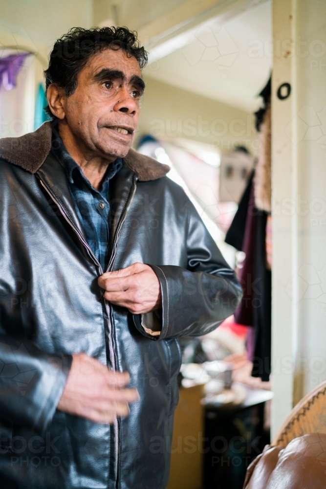 Aboriginal Man Standing while Doing Up his Jacket - Australian Stock Image