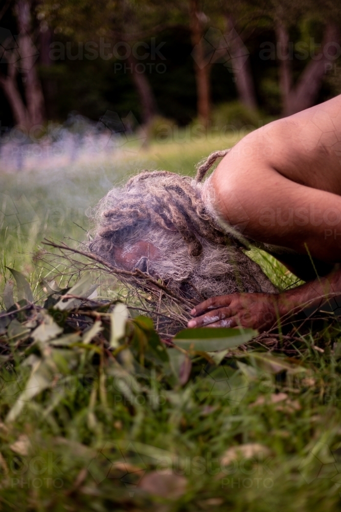 Aboriginal man starting a smoking ceremony - Australian Stock Image