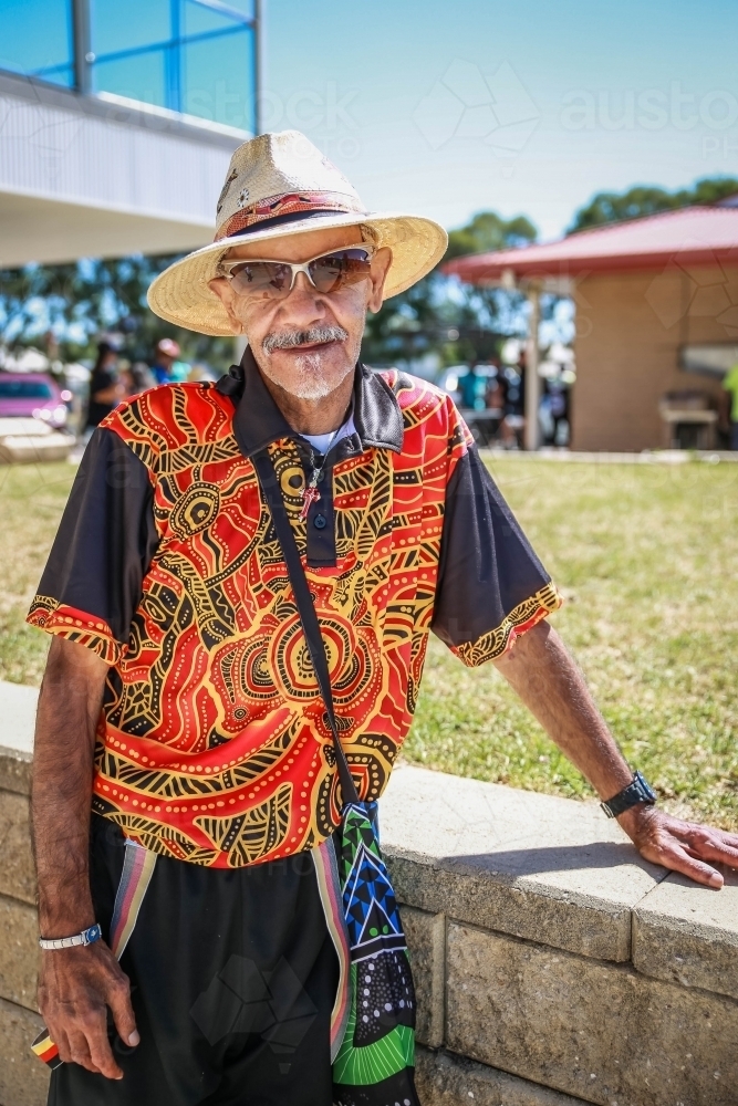 Aboriginal man wearing hat and glasses leaning on brick wall - Australian Stock Image