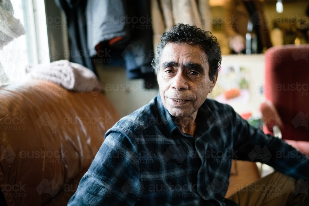 Aboriginal Man wearing plaid shirt Seated on a Couch - Australian Stock Image