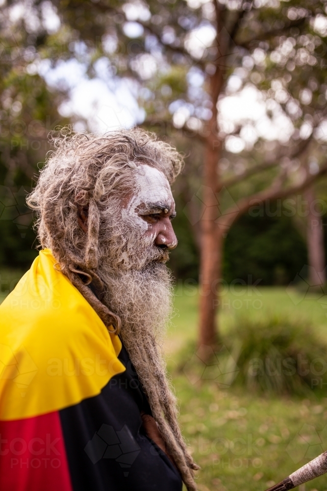 Aboriginal man wearing the Aboriginal flag around his shoulders - Australian Stock Image