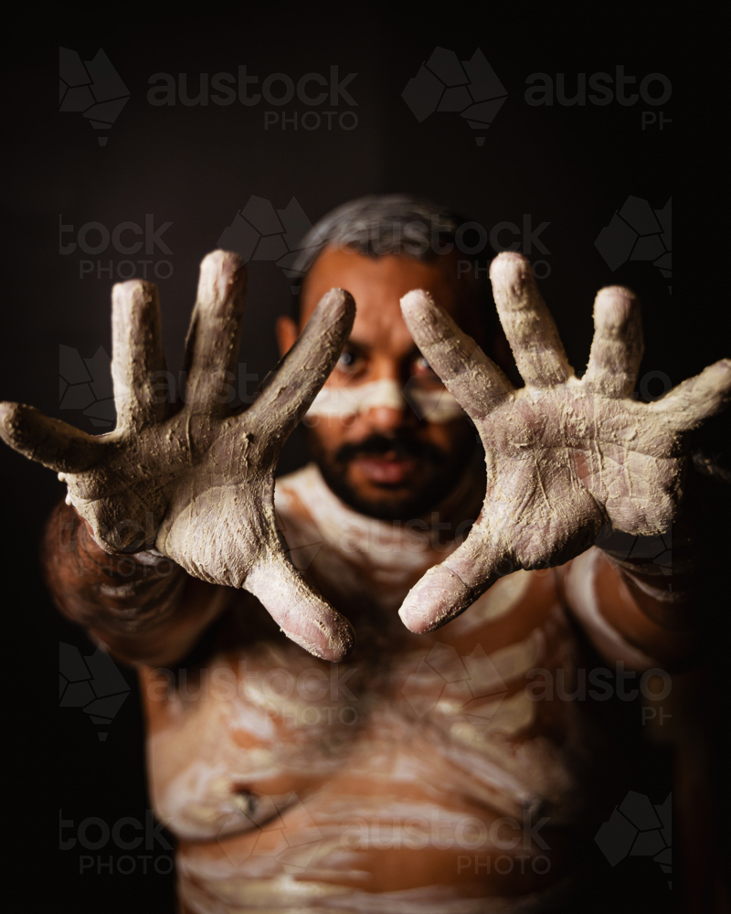 Aboriginal man with body paint extending his palms in front - Australian Stock Image