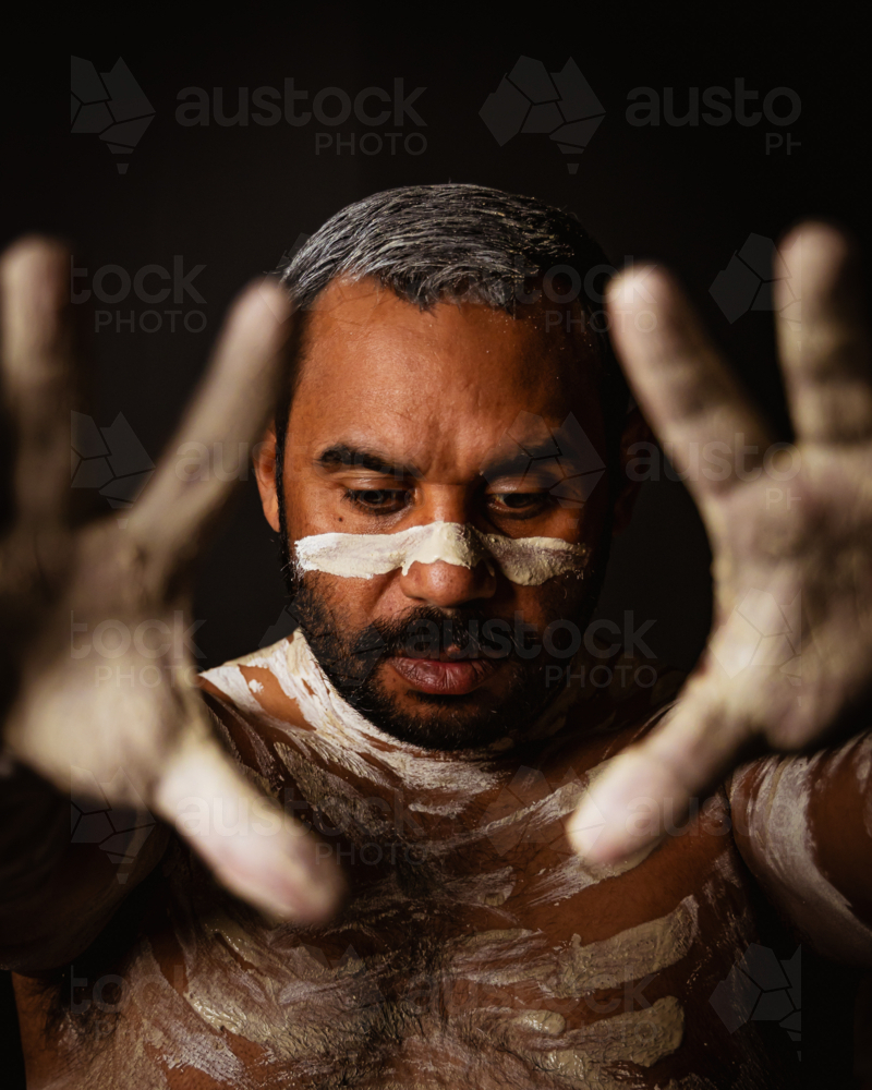 Aboriginal man with body paint extending his palms in front - Australian Stock Image