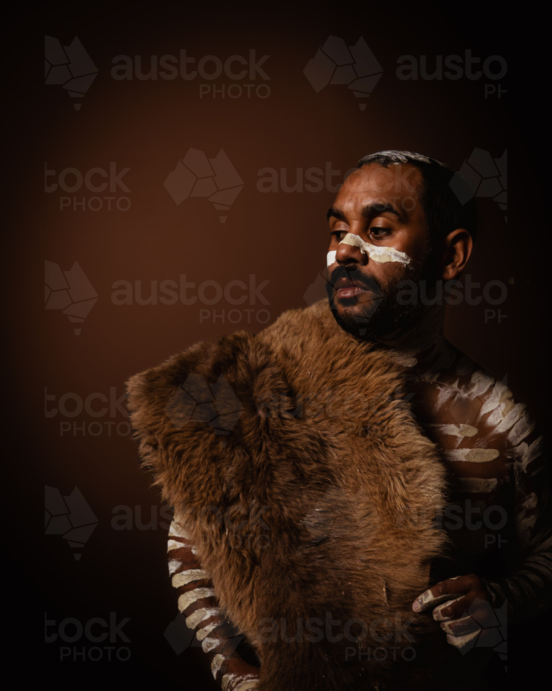 Aboriginal man with kangaroo skin looking to the side - Australian Stock Image