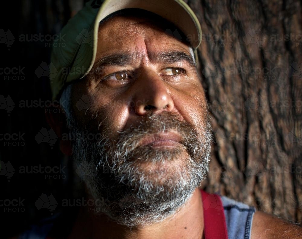 Aboriginal Man with Tree Trunk in Background - Australian Stock Image