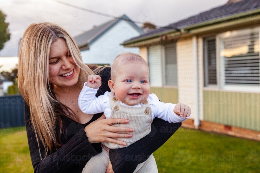 Aboriginal mother and child together outside home in soft winter light - Australian Stock Image