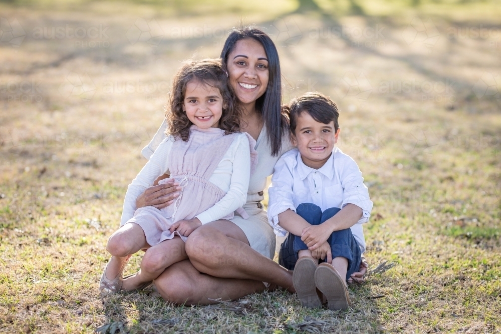 Aboriginal mother sitting with twin mixed race children - Australian Stock Image
