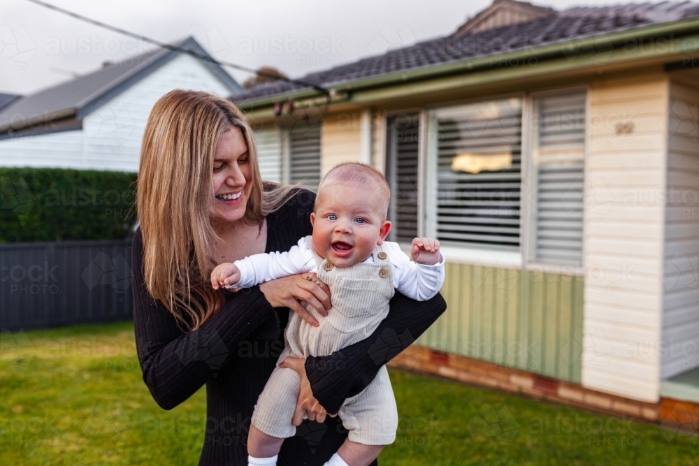 Aboriginal mum and baby outside home smiling together - Australian Stock Image