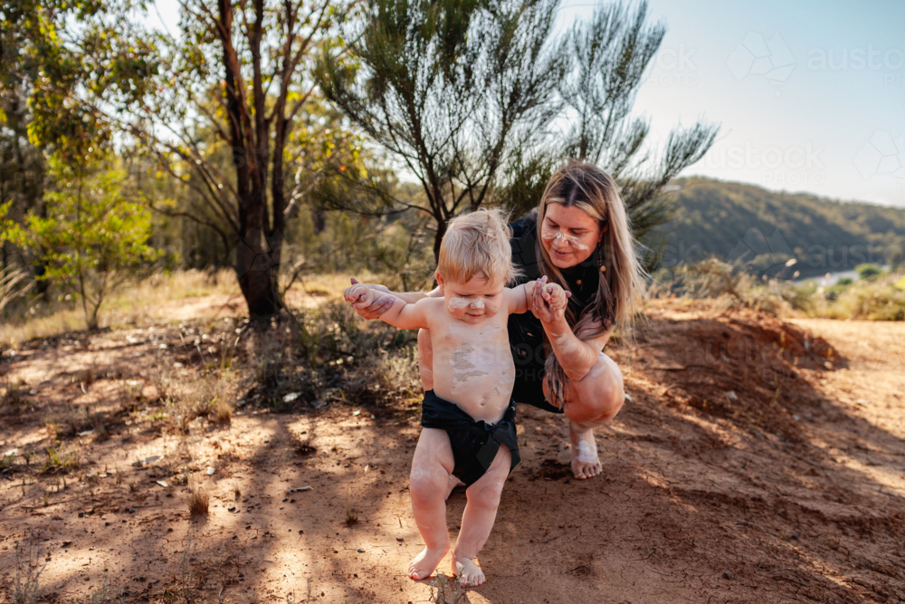 Aboriginal mum with her baby boy together by cliff on country in Australian bushland - Australian Stock Image