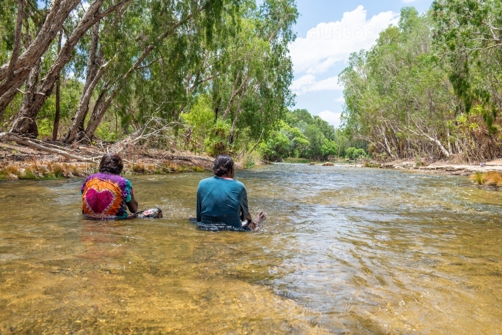 Aboriginal people sitting in river - Australian Stock Image
