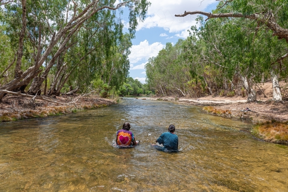 Aboriginal people sitting in river - Australian Stock Image