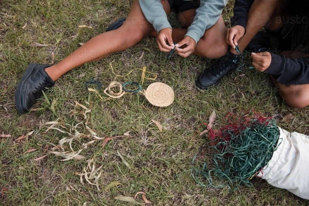 Aboriginal people sitting on grass, basket weaving together : Austockphoto Aboriginal people sitting on grass, basket weaving together - Australian Stock Image