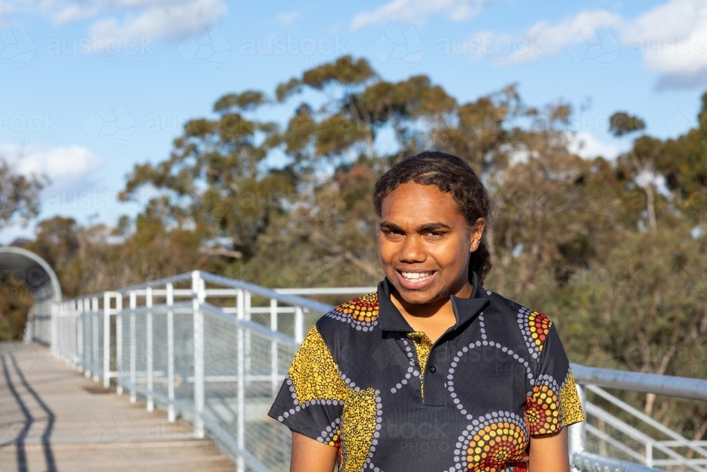 Aboriginal teenage girl walking in the outdoors looking happy - Australian Stock Image