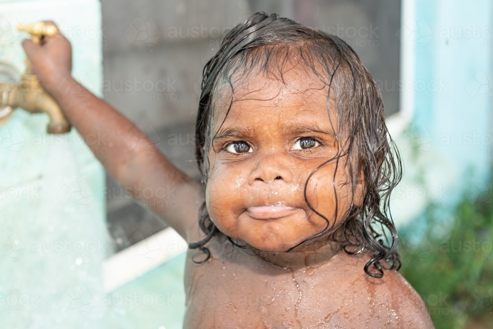 Aboriginal toddler playing in water - Australian Stock Image