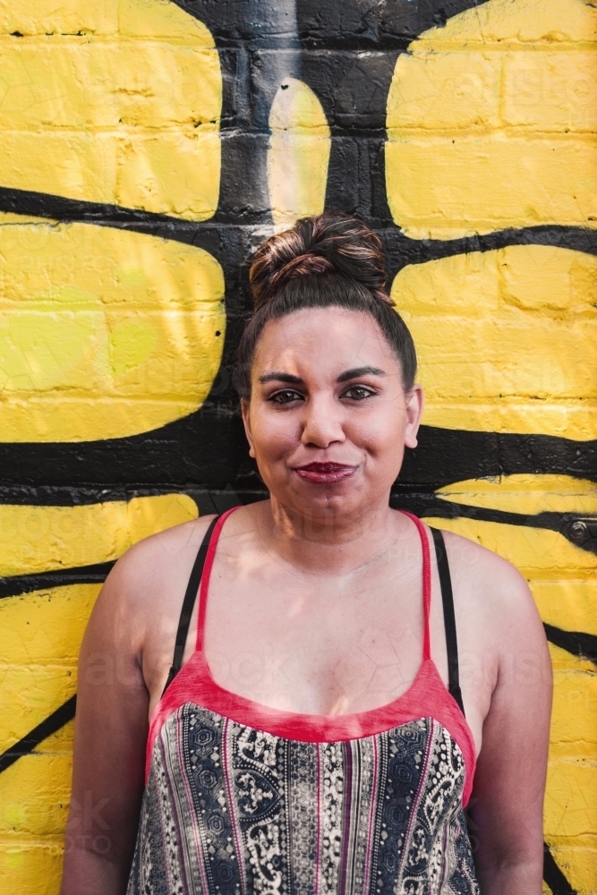aboriginal woman against a painted wall - Australian Stock Image