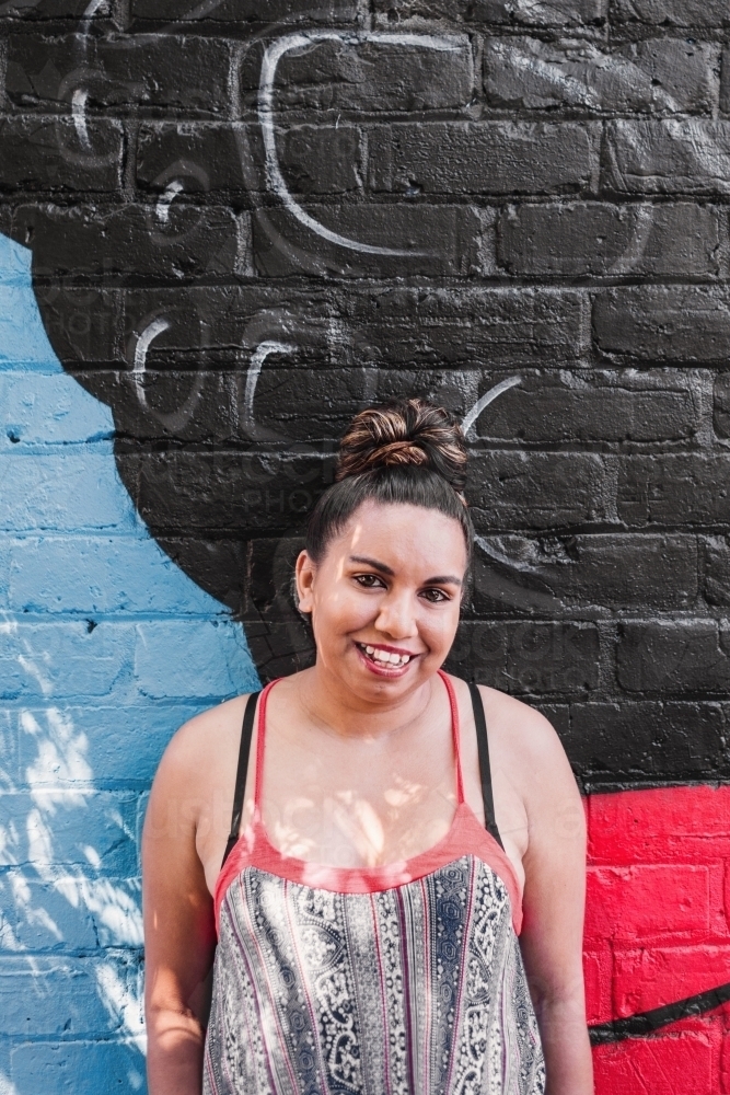 aboriginal woman against a painted wall - Australian Stock Image