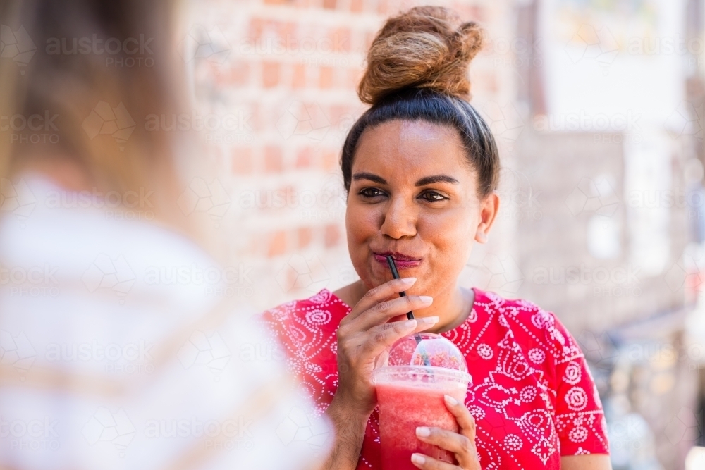 aboriginal woman drinking fruit drink in a cafe - Australian Stock Image