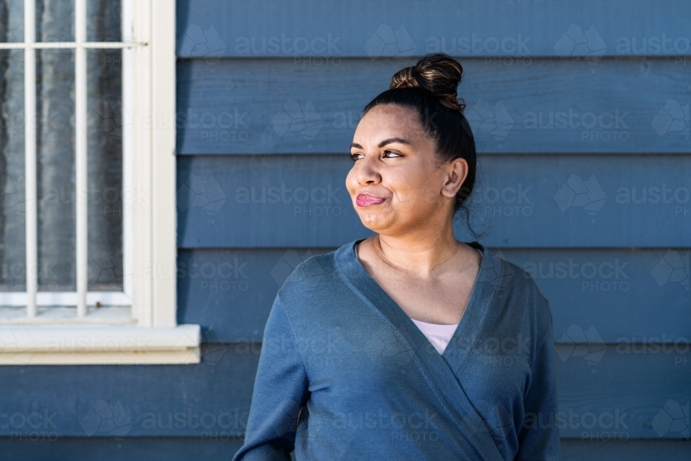 aboriginal woman in front of weatherboard house - Australian Stock Image