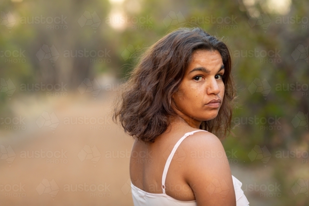 aboriginal woman outdoors looking back over her shoulder - Australian Stock Image