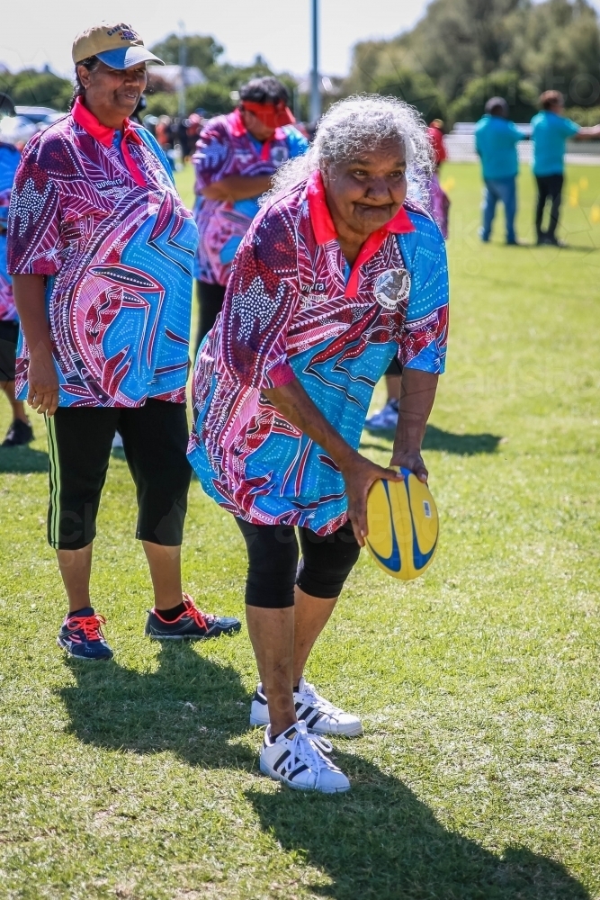 Aboriginal woman passing football in game - Australian Stock Image