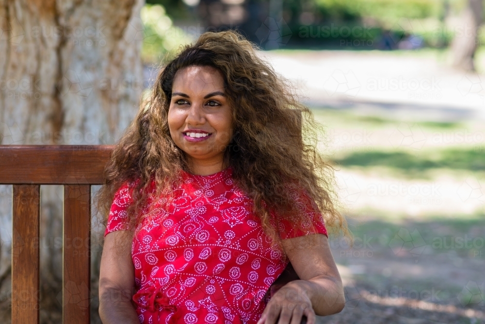 aboriginal woman sitting on a bench in a park - Australian Stock Image