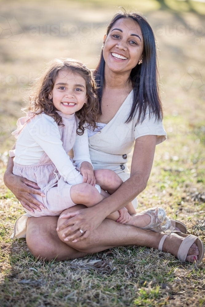 Image of Aboriginal woman sitting with mixed race child on lap smiling Austockphoto
