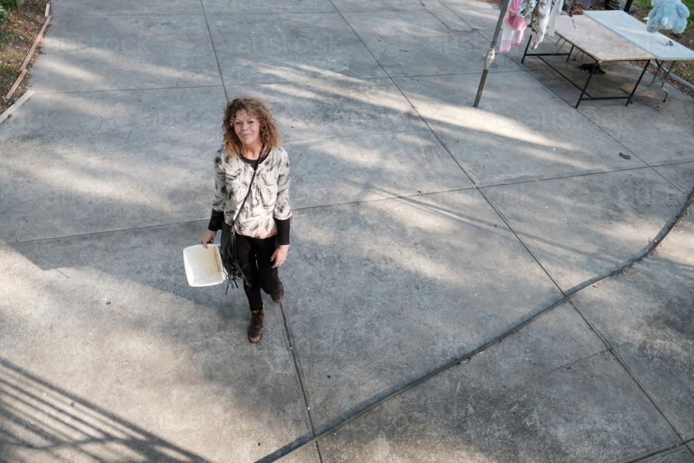Aboriginal Woman walking on the pavement in the backyard - Australian Stock Image