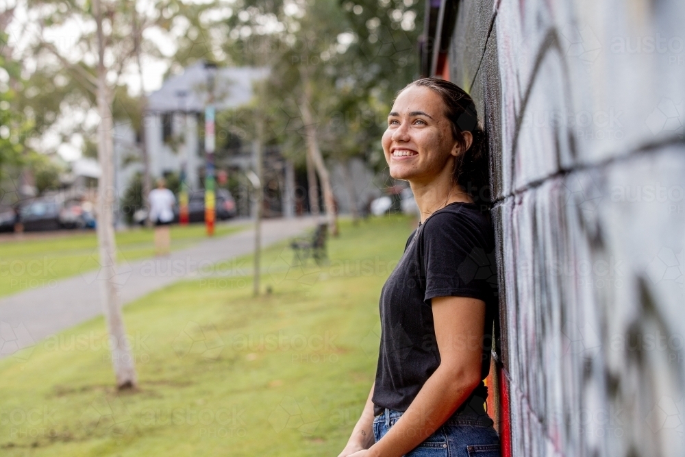 Aboriginal woman wearing a black tshirt smiling and looking out - Australian Stock Image