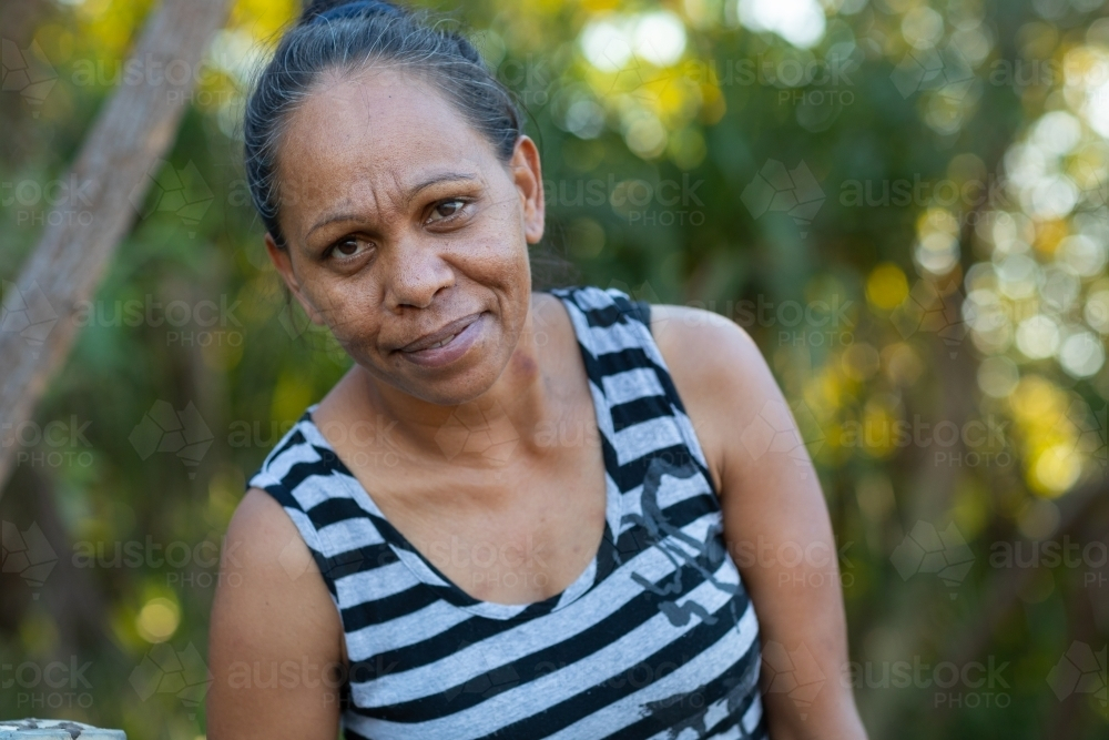 Aboriginal woman wearing striped shirt leaning forward - Australian Stock Image
