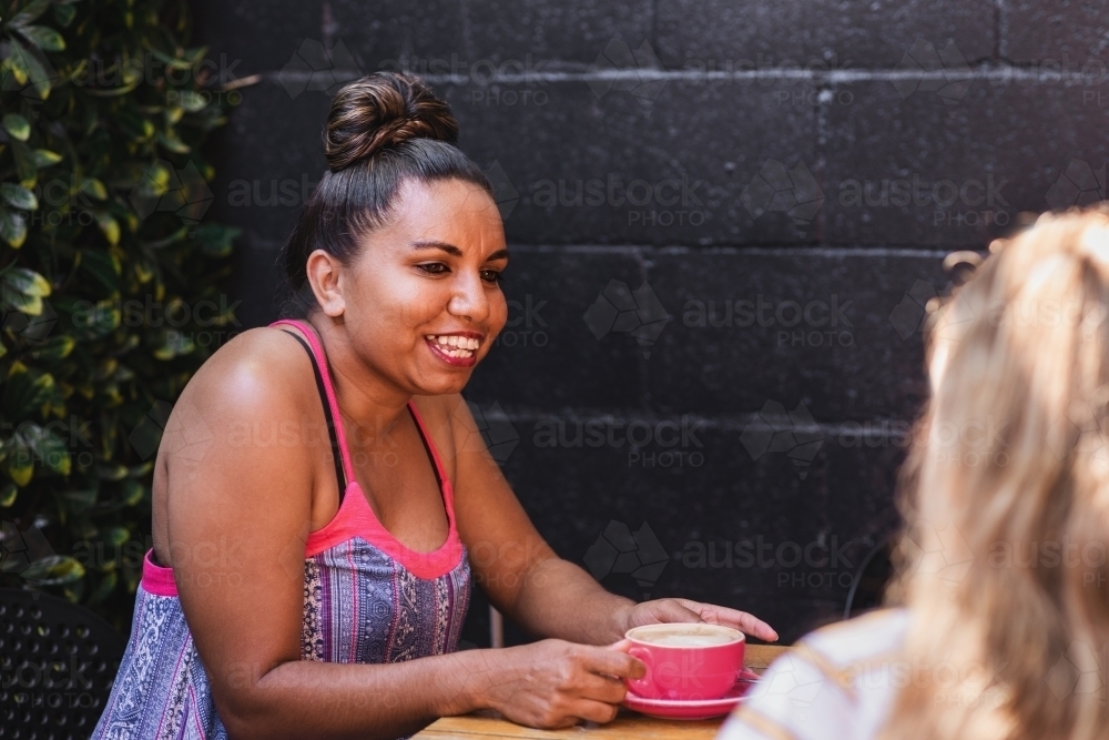 aboriginal woman with coffee in a cafe - Australian Stock Image