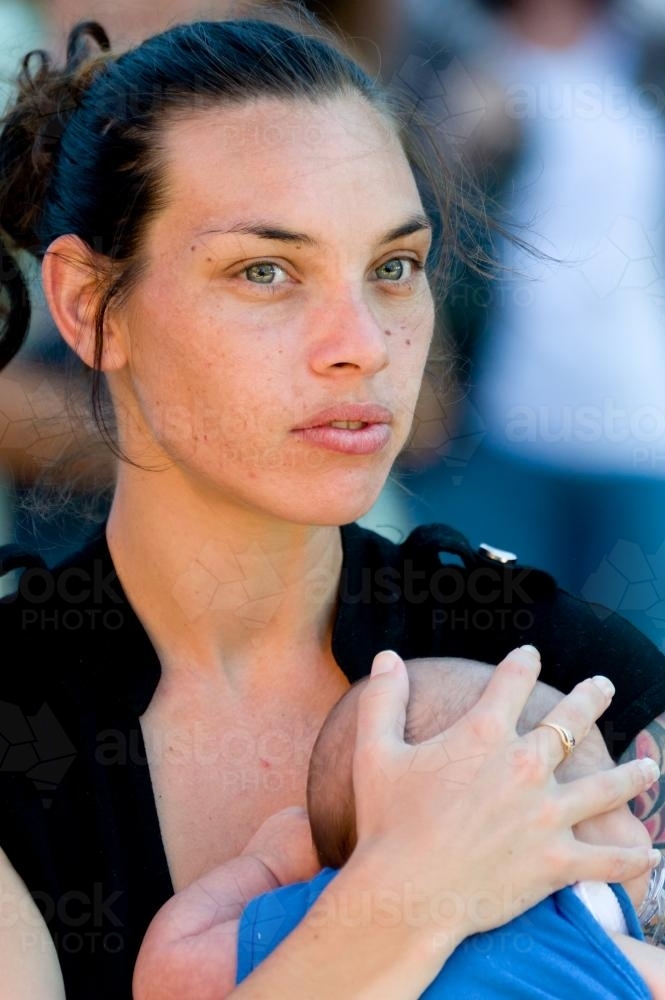 Aboriginal Woman with Concerned Expression while Holding Baby - Australian Stock Image