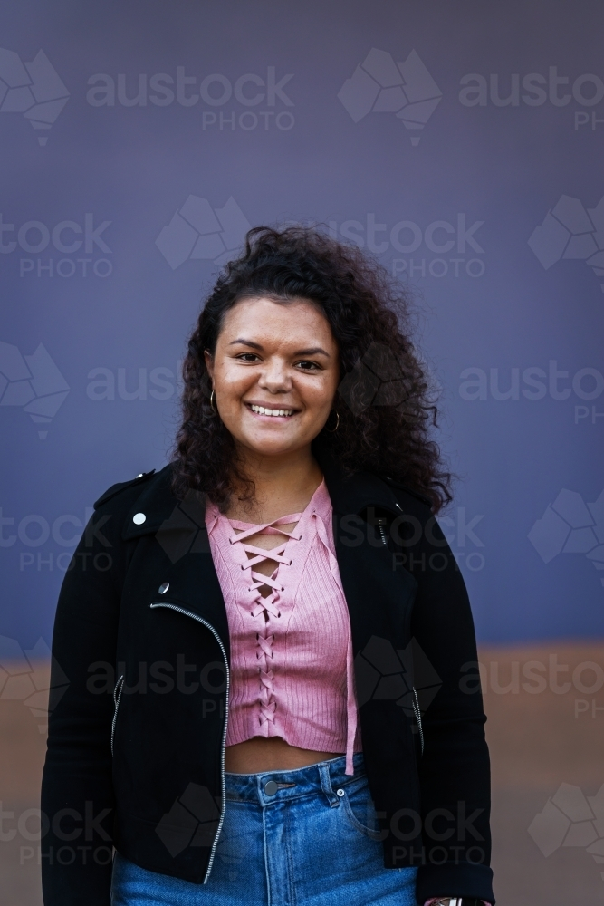 aboriginal woman with curly hair wearing jacket smiling - Australian Stock Image