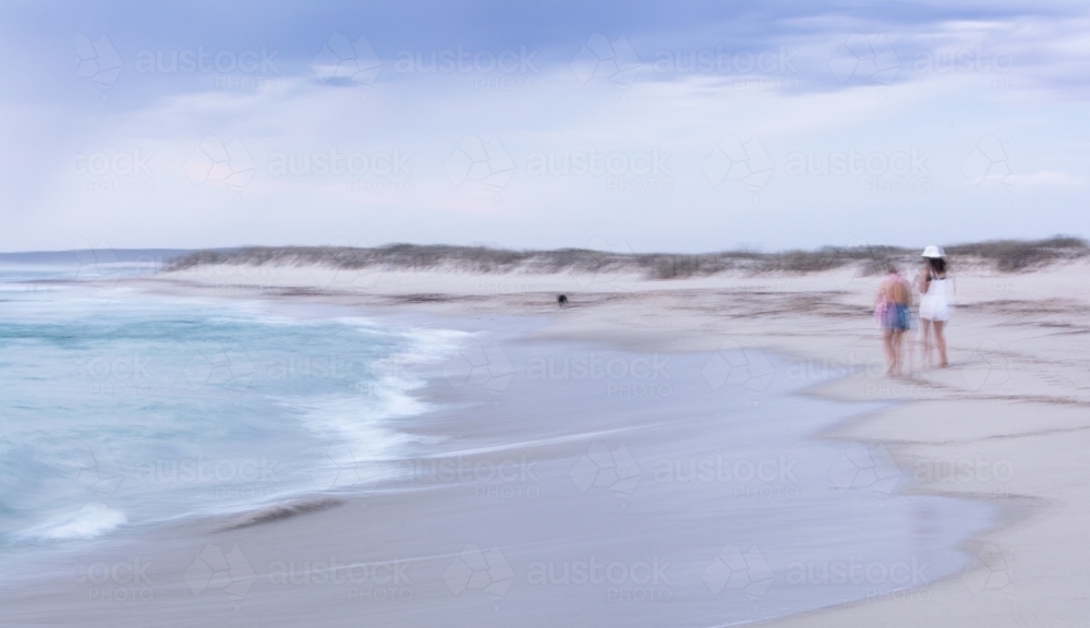 Abstract photo of people walking dog along a beach - Australian Stock Image
