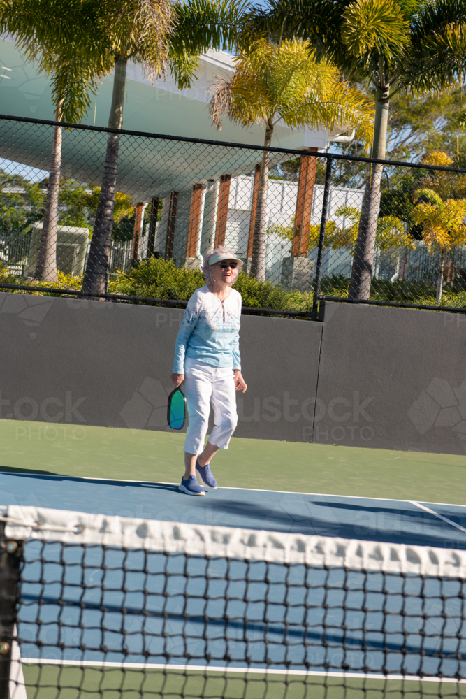 active senior woman playing pickleball outdoors - Australian Stock Image