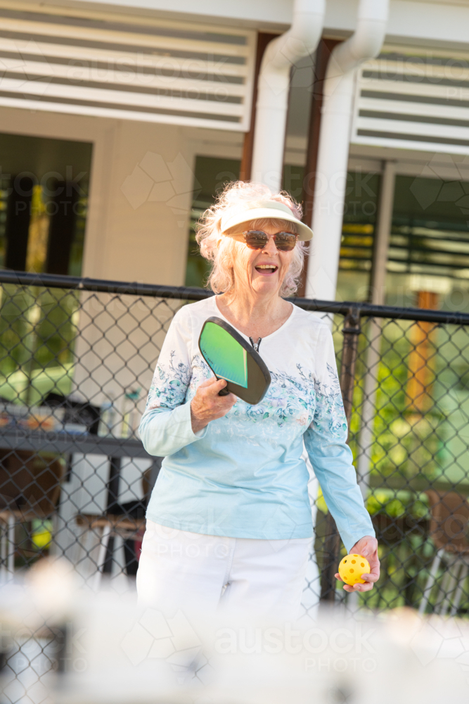 active senior woman playing pickleball outdoors - Australian Stock Image