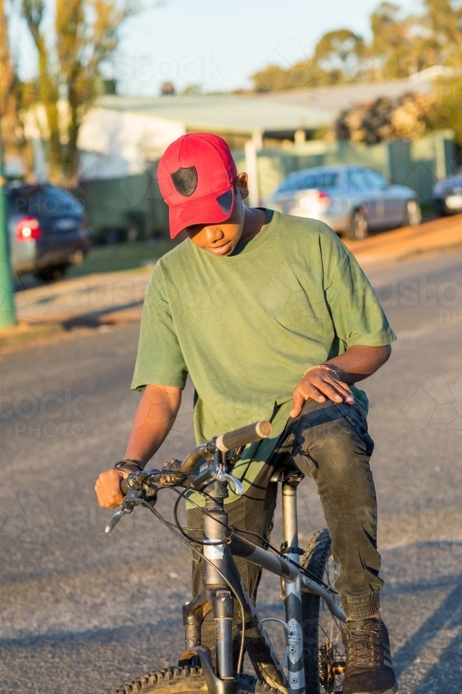 adolescent kid on bike in street in country town - Australian Stock Image