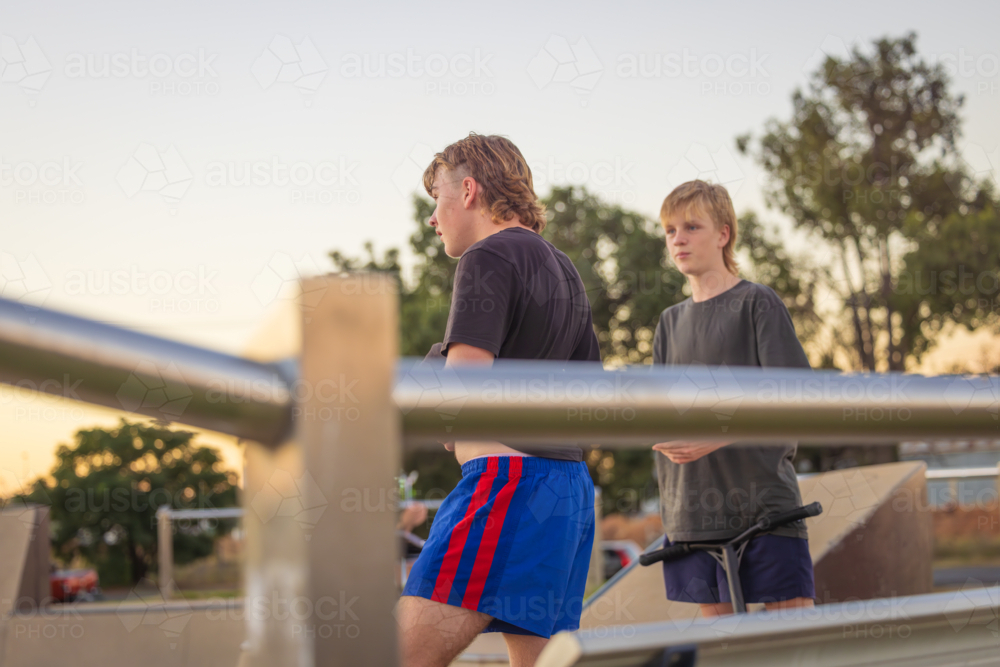 Adolescent teenage boys hanging out at the skate park with scooters - Australian Stock Image