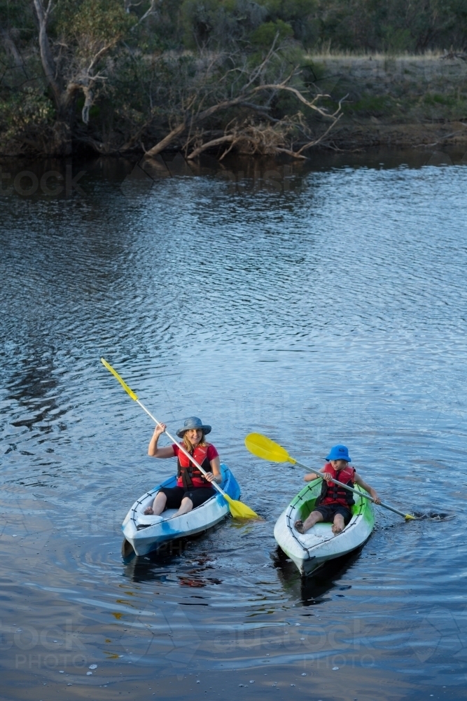 Adult and child paddling canoes on river - Australian Stock Image
