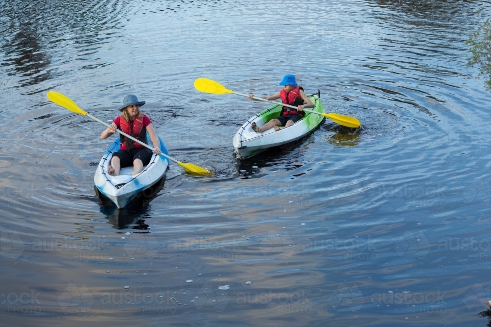 Adult and child paddling kayaks - Australian Stock Image