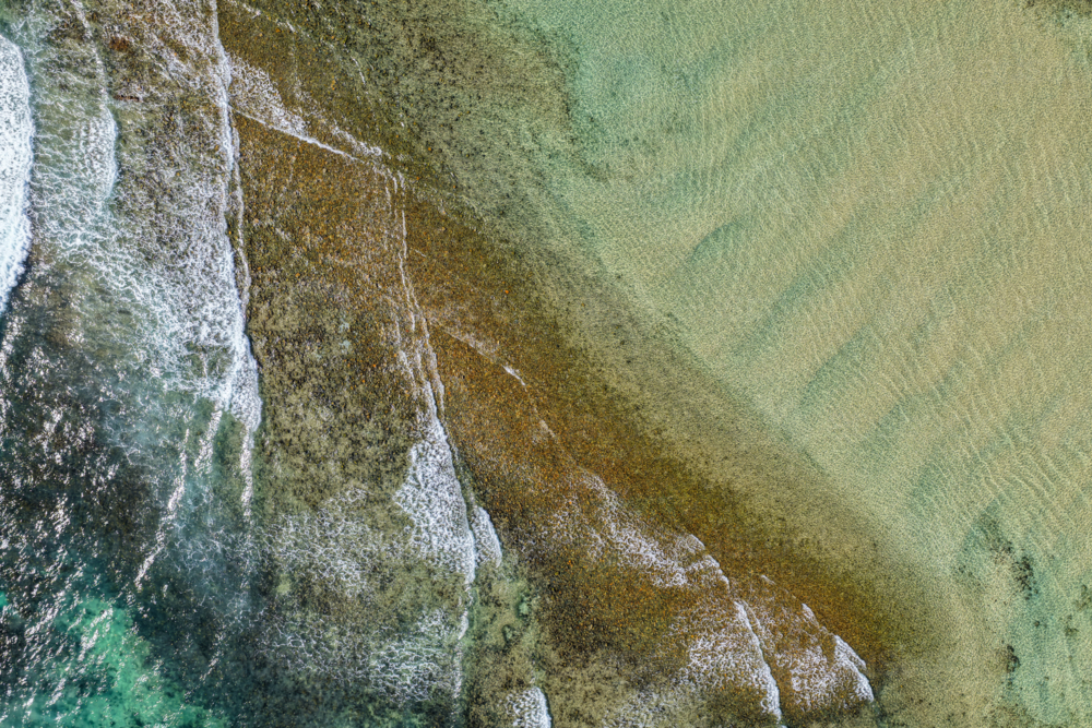 Aerial downward view of ocean waves crashing over the rugged rocky coastline at Brooms Head - Australian Stock Image