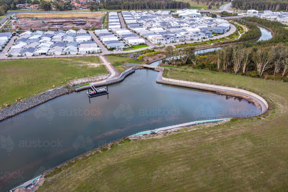 Aerial drone view looking down over a jetty extending into a calm water inlet at Pipers Bay. - Australian Stock Image