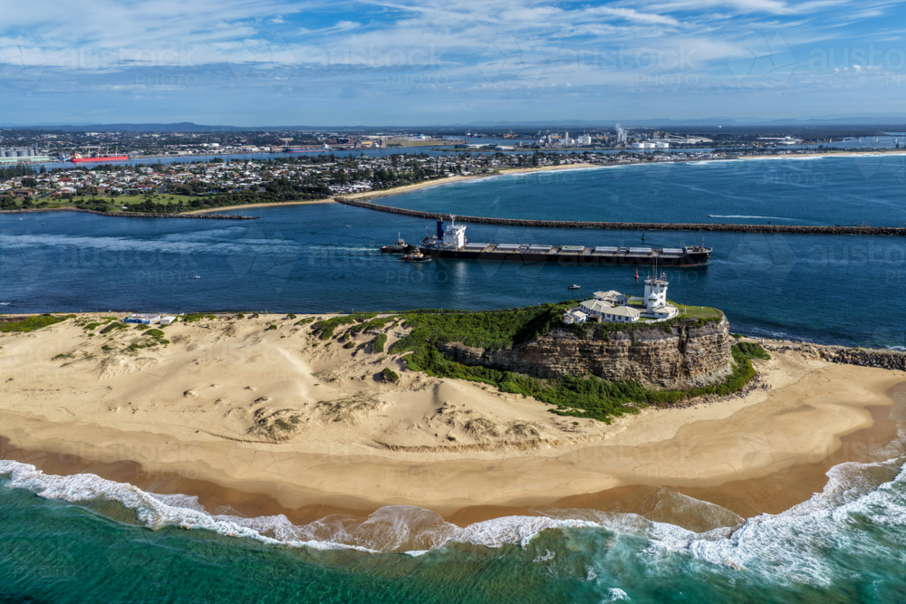 Aerial drone view of Nobbys Lighthouse and Nobbys Beach with a large cargo ship being escorted. - Australian Stock Image