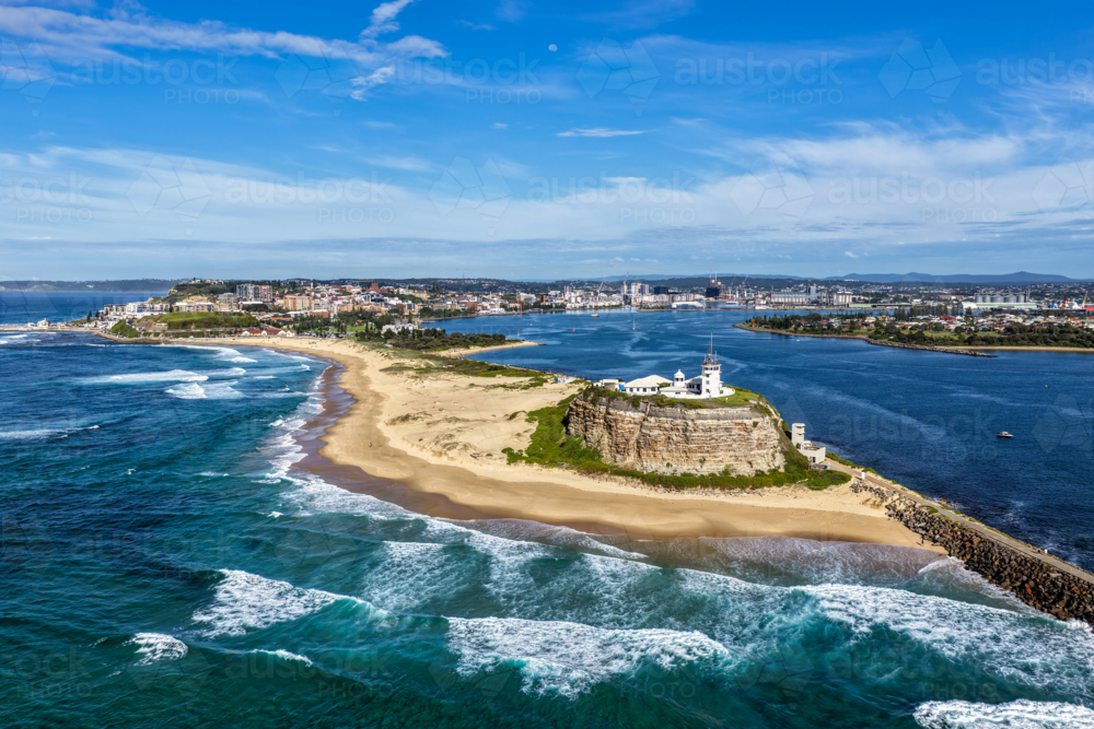 Aerial drone view of Nobbys Lighthouse and sandy Nobbys Beach with Newcastle city skyline. - Australian Stock Image