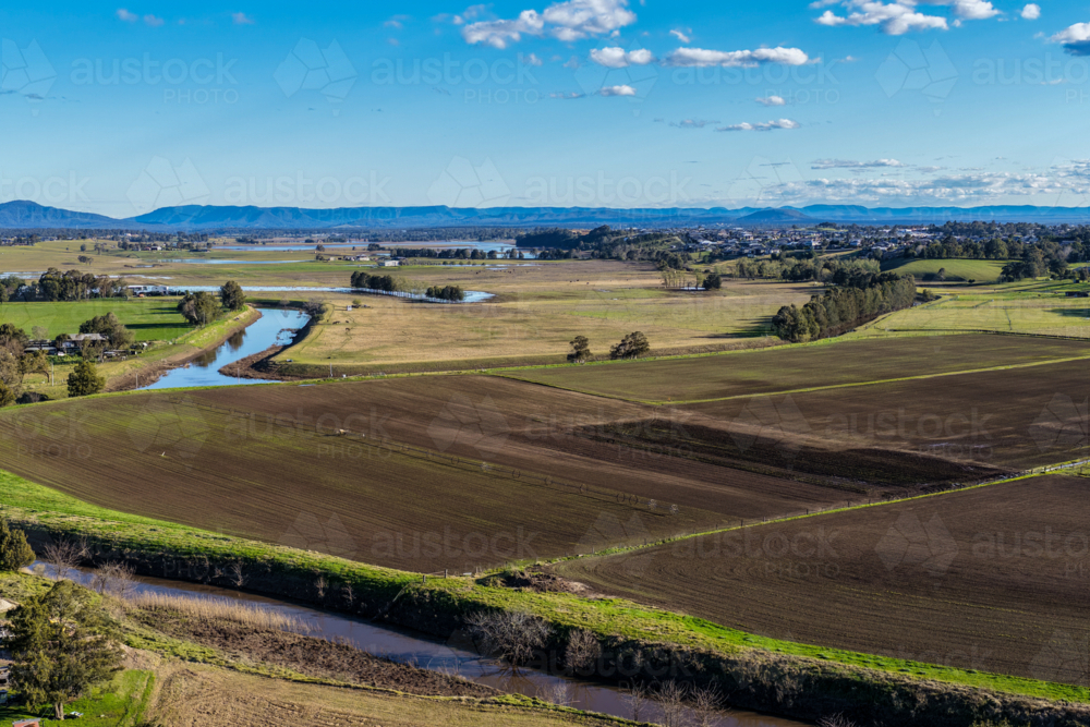 Aerial drone view of rural farmland in Maitland, New South Wales, Australia beneath cloudy blue sky - Australian Stock Image