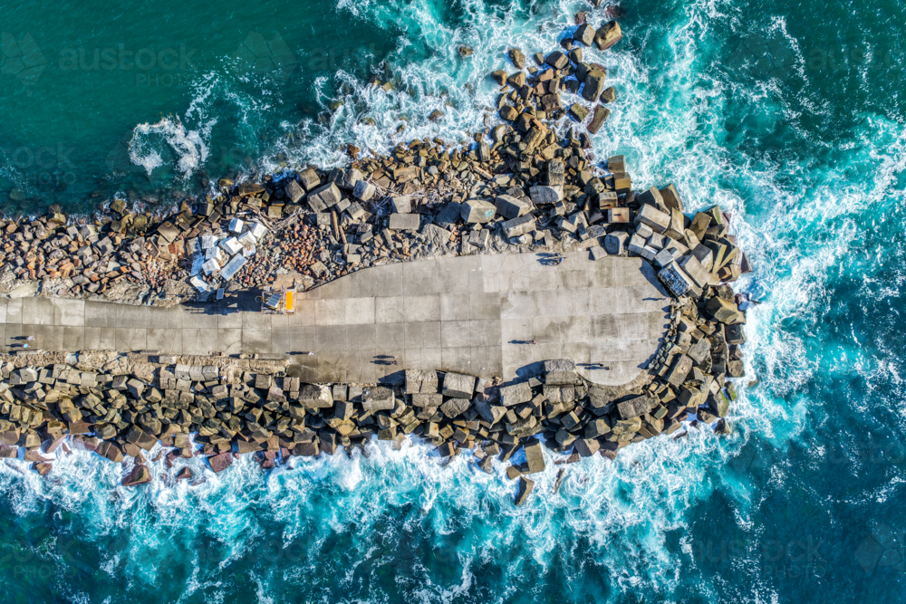 Aerial drone view of the Newcastle breakwall extending into the Pacific Ocean with waves crashing. - Australian Stock Image