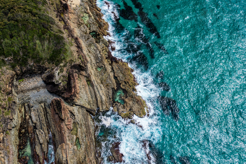 Aerial drone view over McBrides rockpool showing the natural rock formation along a rugged coastline - Australian Stock Image