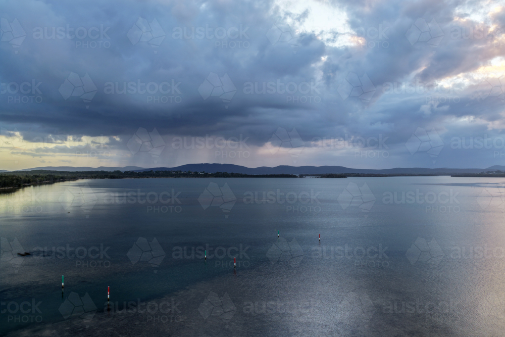 Aerial drone view over Pipers Bay in Forster, NSW, Australia with the sun setting behind the clouds - Australian Stock Image